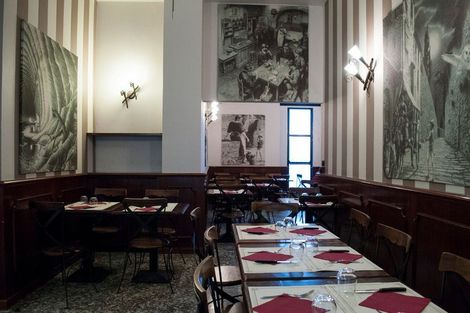Un ristorante con tavoli e sedie e quadri sul muro