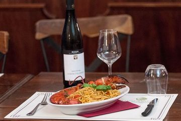 Una bottiglia di vino è posta accanto a un piatto di cibo su un tavolo.