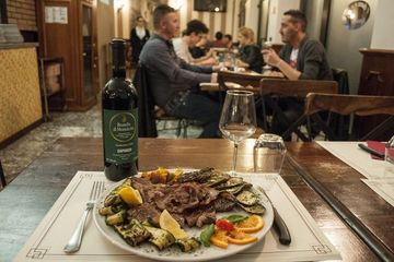 Un piatto di cibo e una bottiglia di vino su un tavolo in un ristorante.