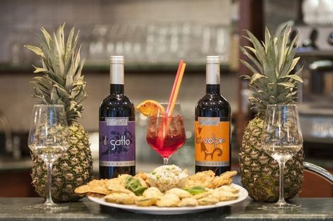 Due bottiglie di vino, due ananas e un piatto di cibo su un bancone del bar.