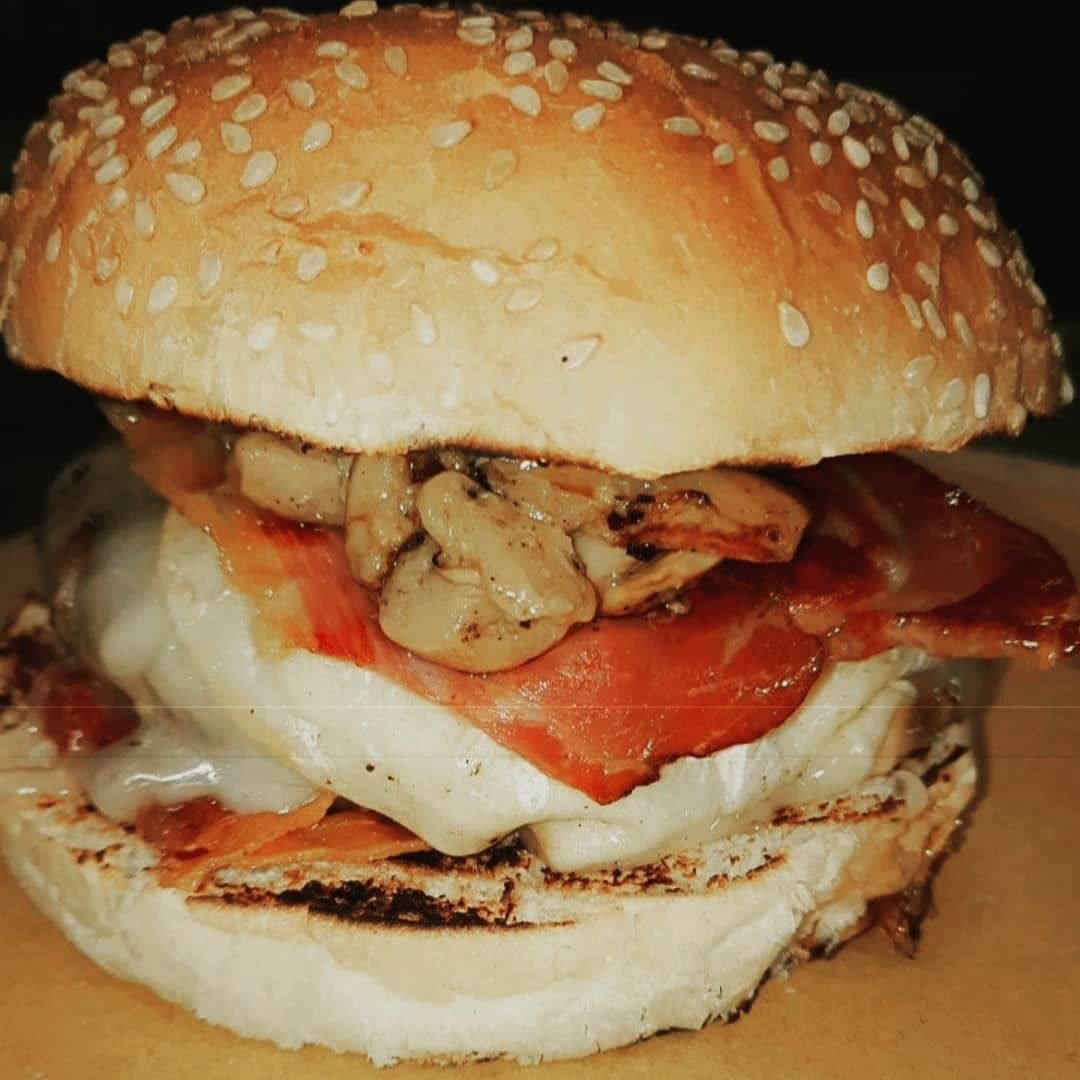 Hamburger in un panino ai semi di sesamo con pancetta, formaggio e funghi.