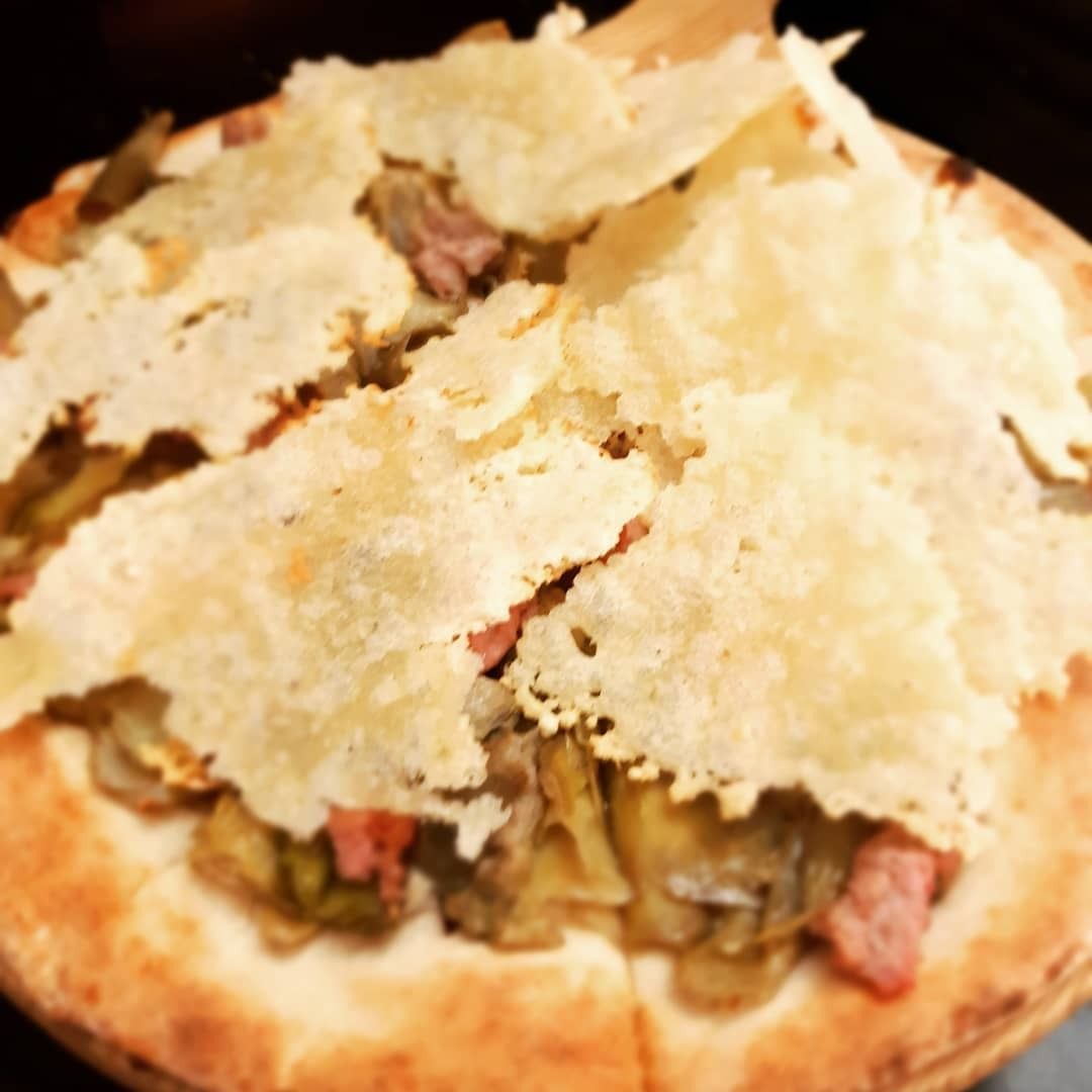 Pizza condita con cuori di carciofo, pancetta e formaggio croccante.
