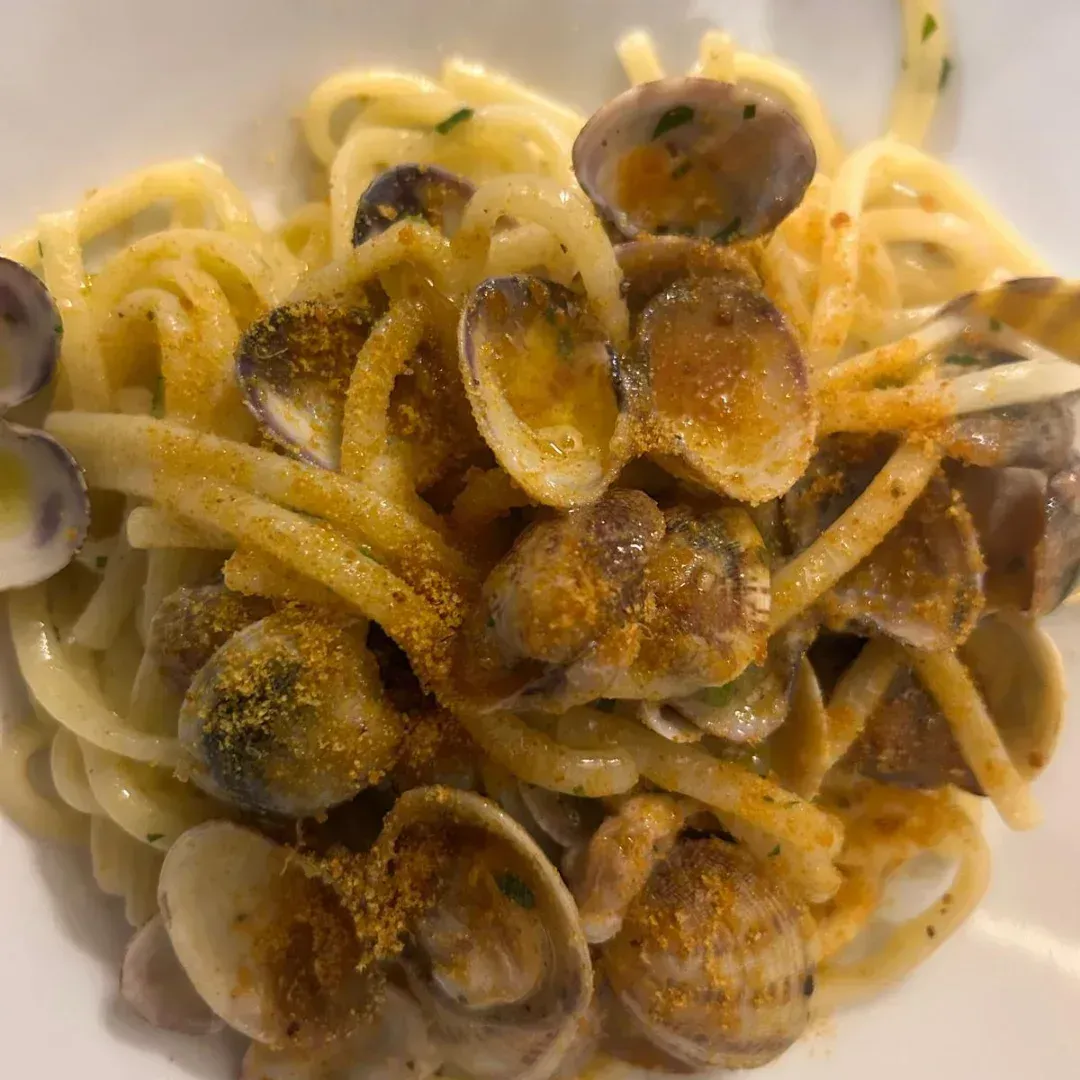 Piatto di pasta con vongole, giallo dorato, primo piano, fotografia di cibo.