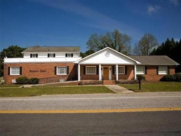 A large brick building with a white roof and a porch
