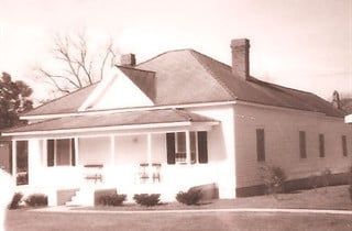A black and white photo of a house with a porch