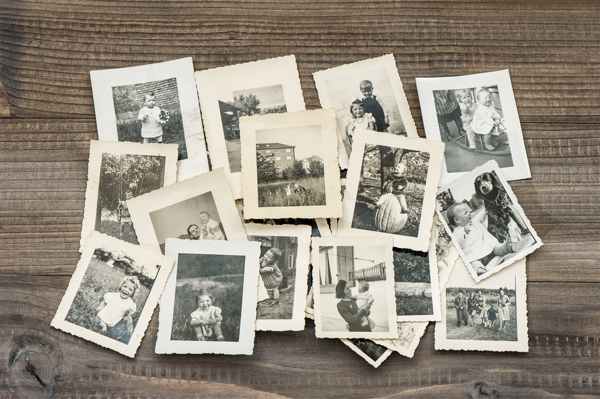 A pile of old black and white photos on a wooden table.