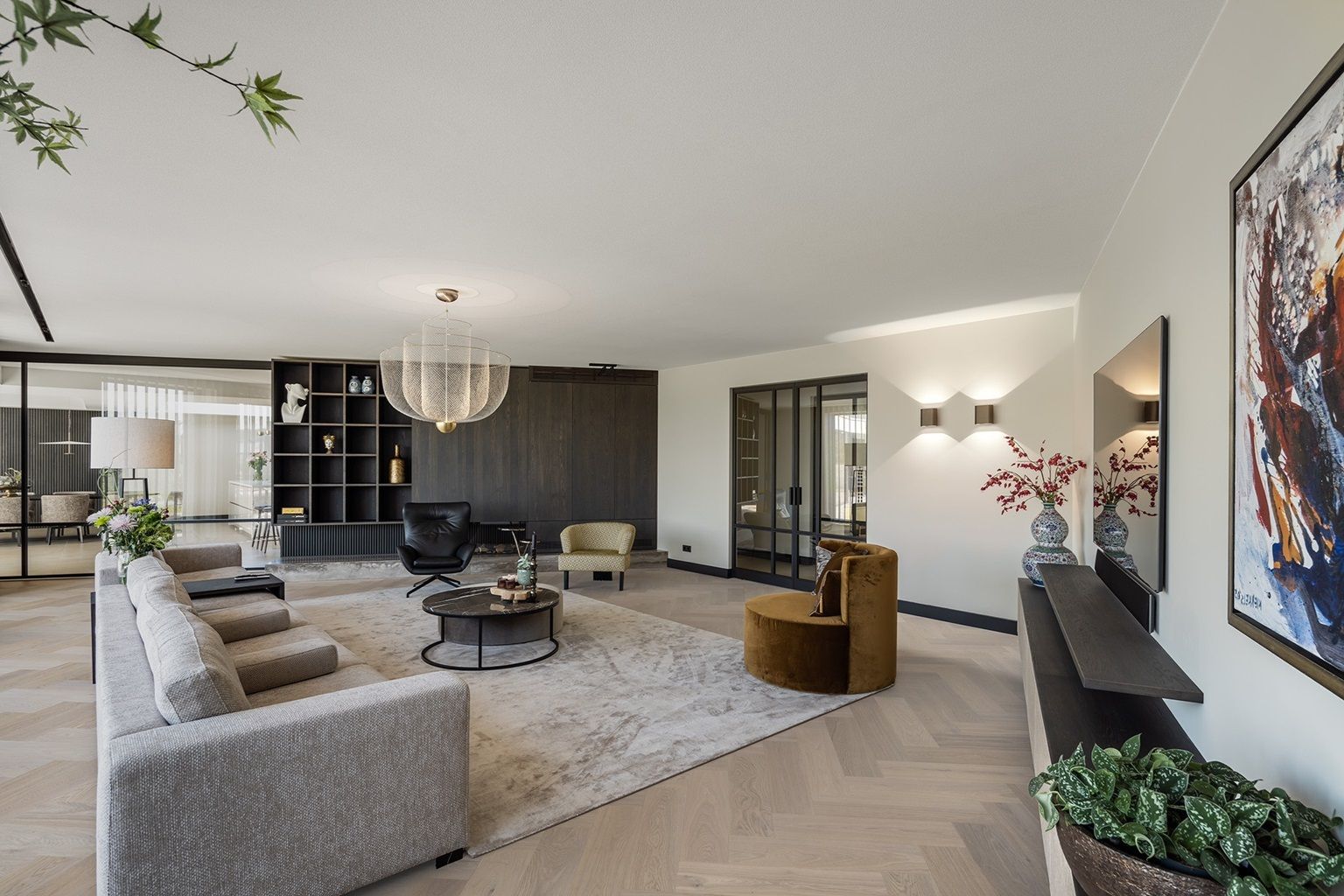 Moderne, minimalistische woonkamer met grijze bank, neutraal vloerkleed, fluwelen fauteuil en groot kunstwerk aan de muur op een visgraatvloer.