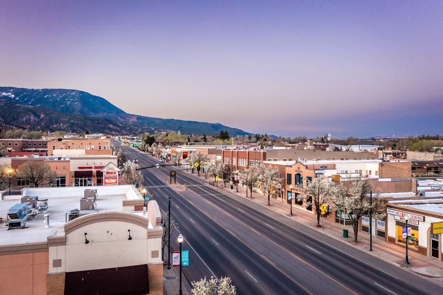 Empty street in a small town, buildings on either side, mountain backdrop, twilight sky.