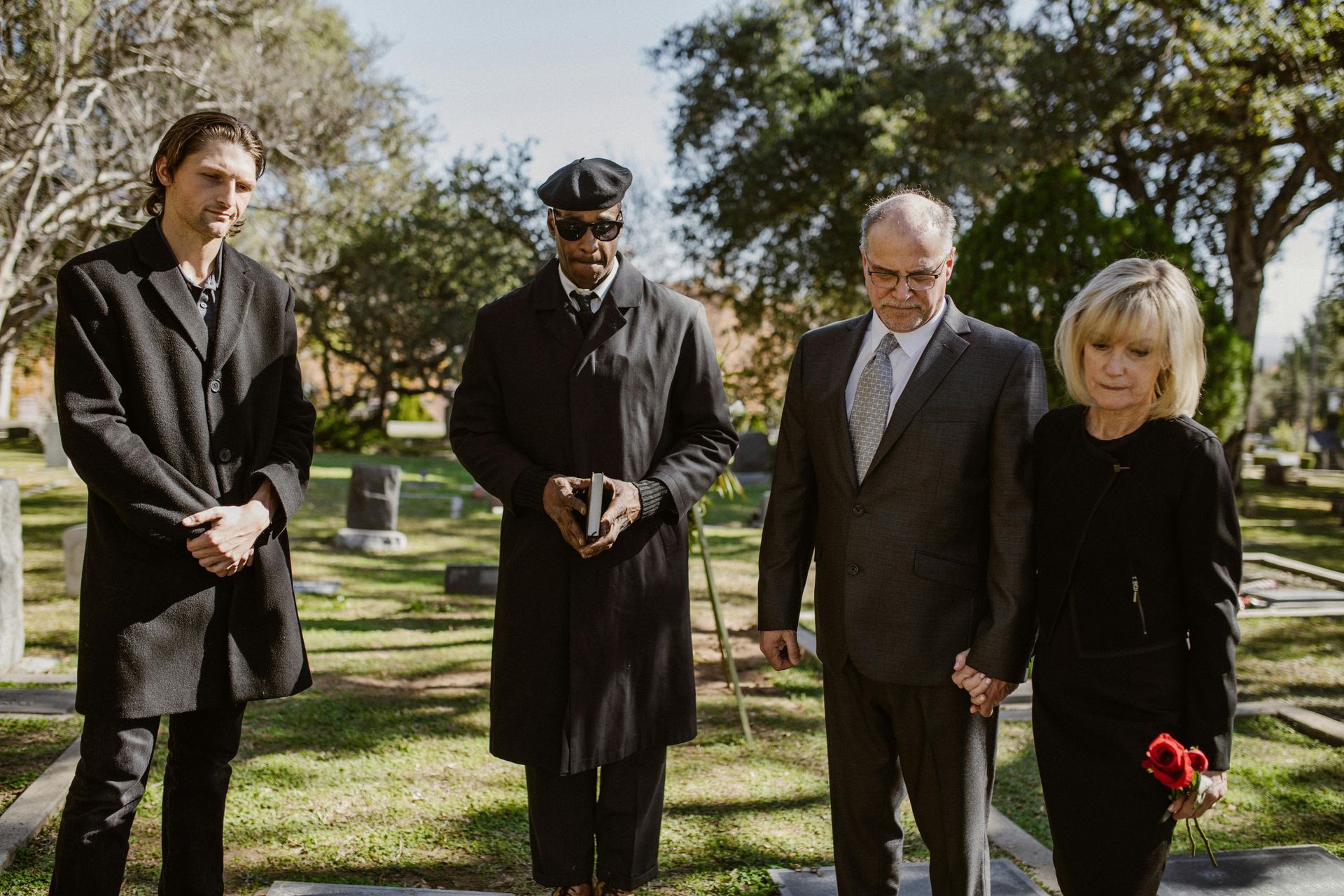 People at a graveside service. Cemetery setting. Mourners in black.