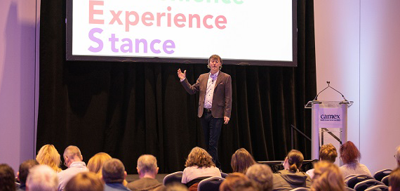 A man is giving a presentation in front of a screen that says experience stance