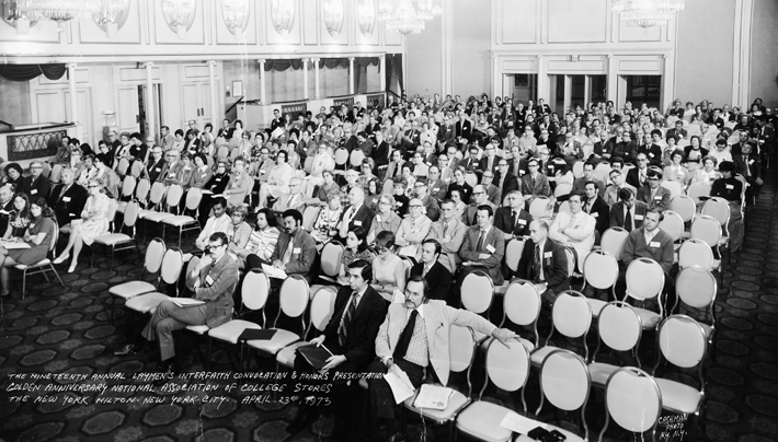 A large group of people are sitting in chairs in a large room.