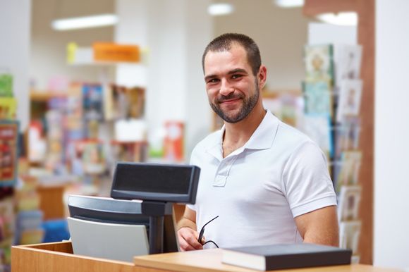 A man is standing behind a counter in a store.