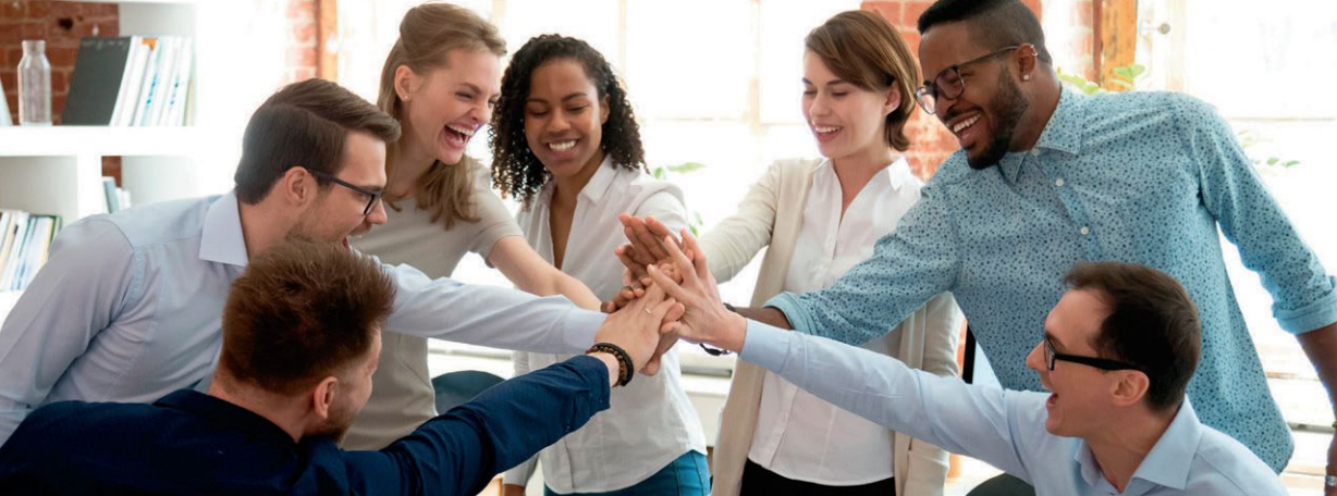 A group of people are putting their hands together in a circle.