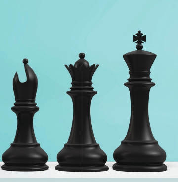 Three black chess pieces are lined up on a table