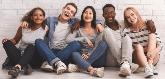 A group of young people are sitting on the floor together.