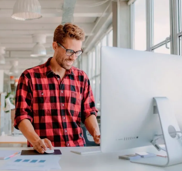 A man in a plaid shirt is working on a computer