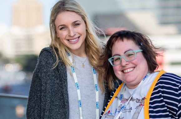 Two women are posing for a picture together and smiling for the camera.