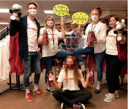 A group of people wearing masks and holding signs that say from the berg and bookshop