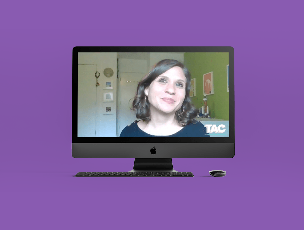 A woman is sitting in front of a computer monitor.