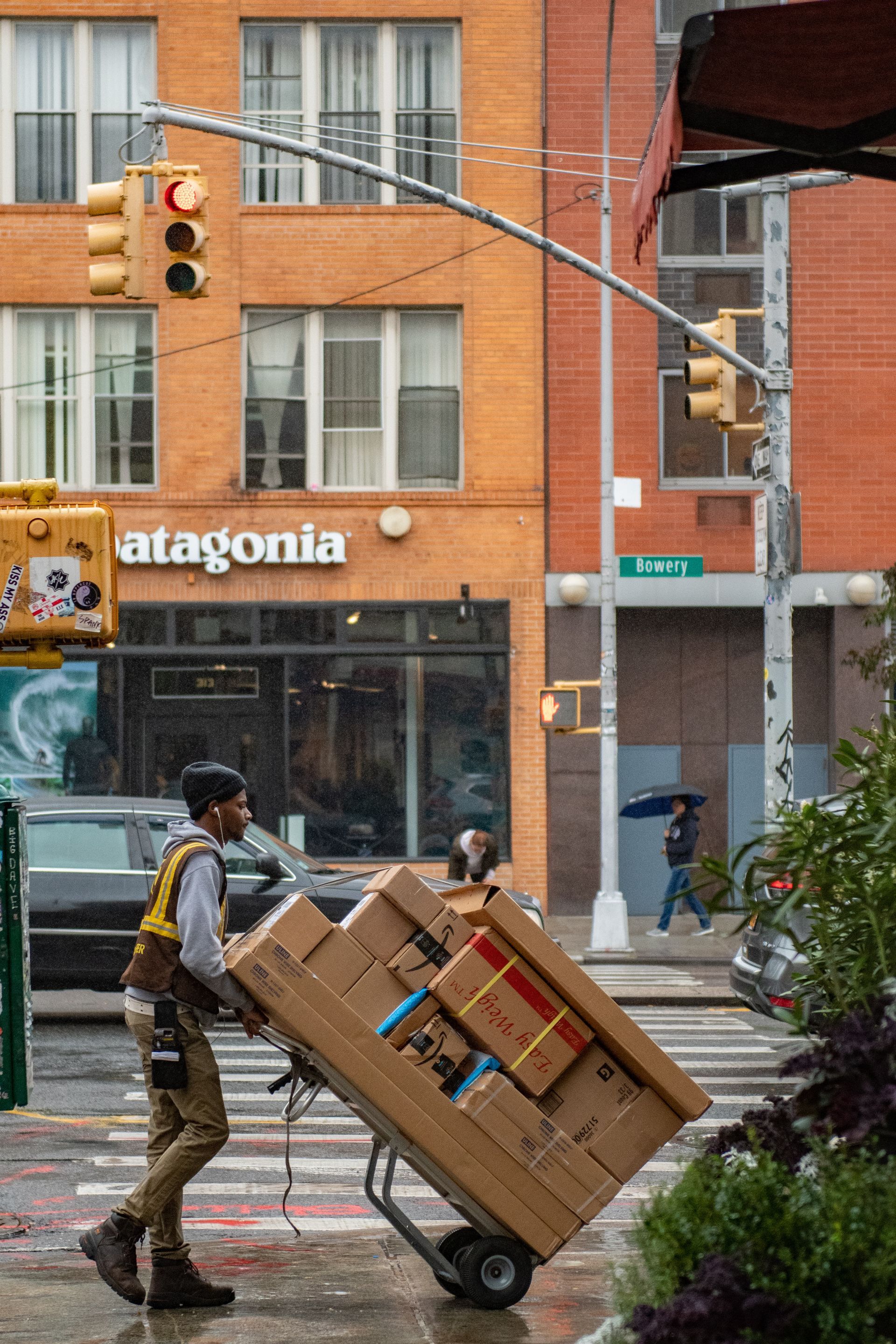 A man is pushing a cart full of boxes on a city street.