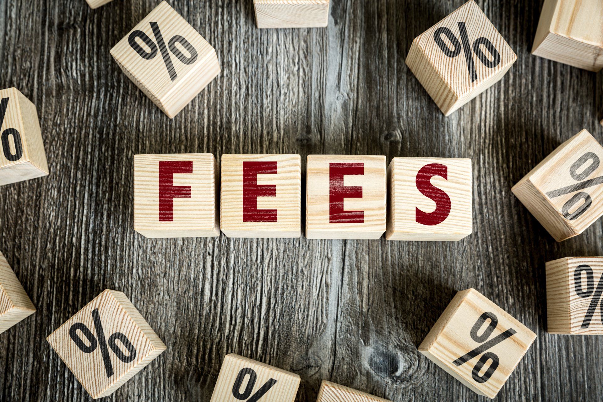 The word fees is written on wooden blocks on a wooden table.