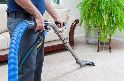 A Person Is Using a Vacuum Cleaner to Clean a White Carpet | Sheboygan, WI | Hoffman's Cleaners LLC