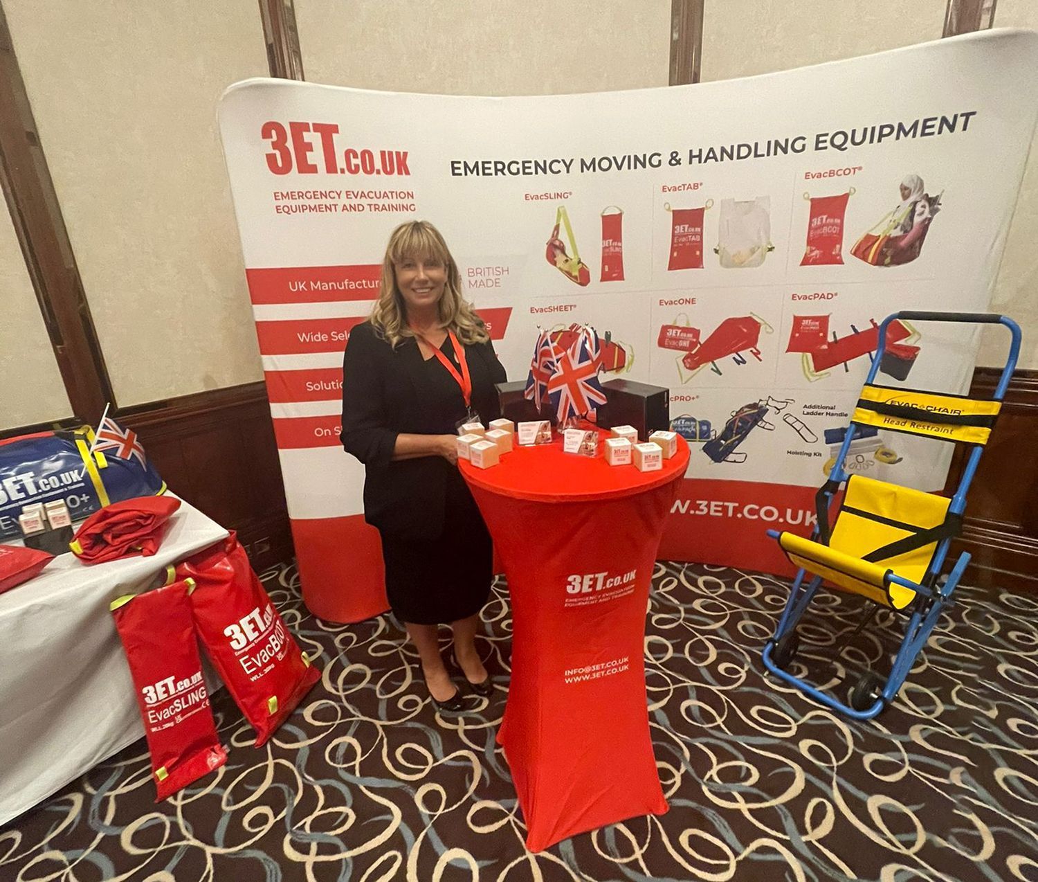 Woman at a trade show booth promoting emergency moving equipment. Booth features equipment and branded banner.