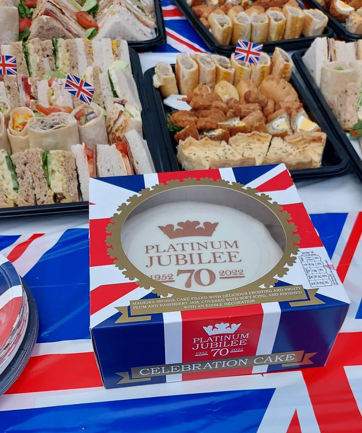 Platinum Jubilee celebration with food platters, a cake box, and a Union Jack tablecloth.