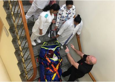 Medical team on stairs, preparing to move a patient in a stretcher.