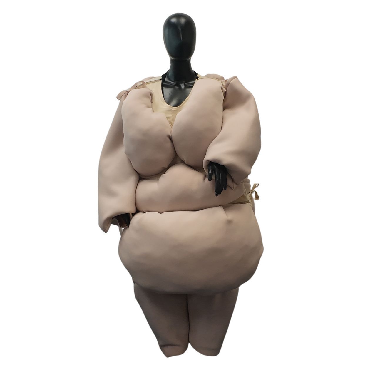 Mannequin in a beige, padded costume resembling a corpulent figure.