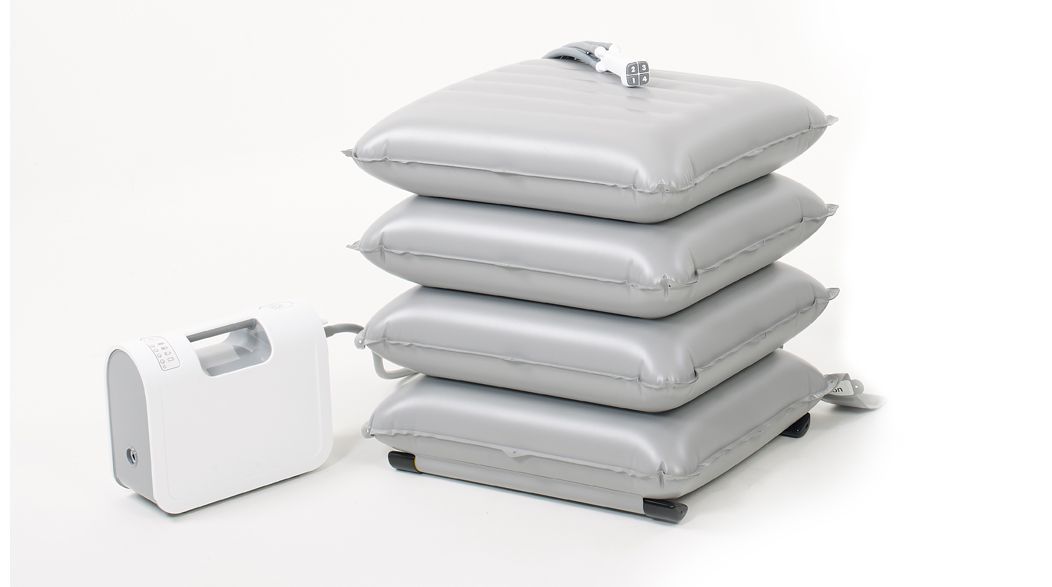 Gray inflatable cushions stacked with a white pump, likely for medical use.