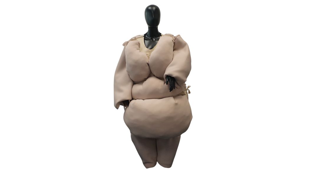 Mannequin in beige, padded clothing, designed to simulate a figure with folds of fat.