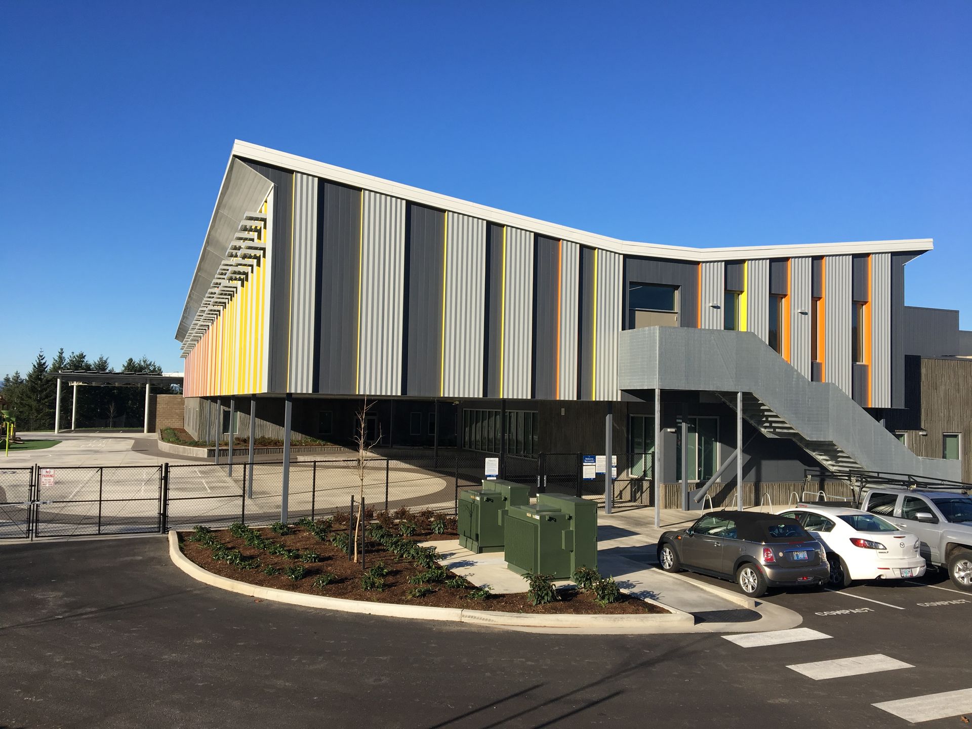 Modern building with striped facade, parking lot, and blue sky
