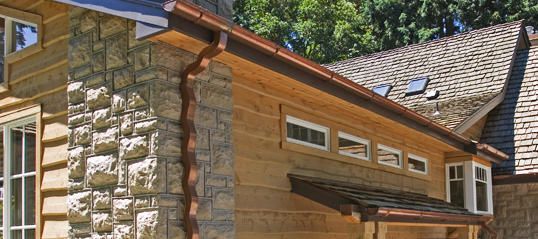 Stone and wood house exterior with a sloped shingle roof and small windows