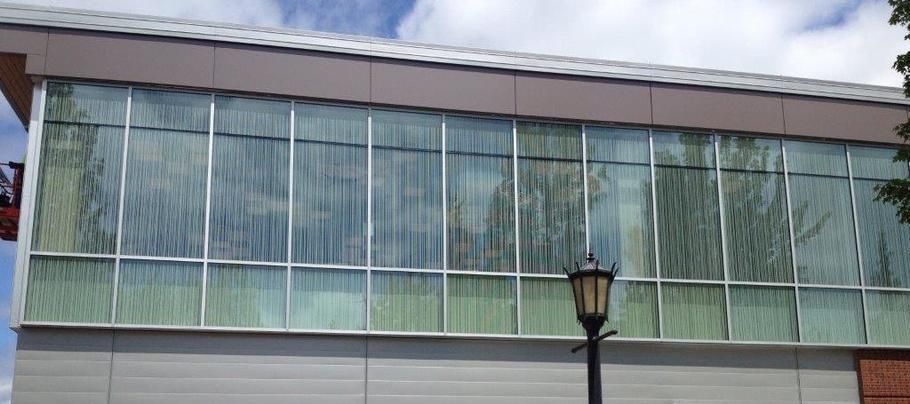 Glass-front building facade with green-tinted windows and a lamppost in front