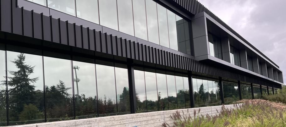 Modern black-and-glass office building with reflective windows and landscaped foreground
