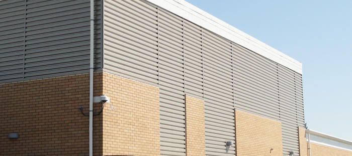 Brick and gray metal building exterior with a security camera mounted on the corner