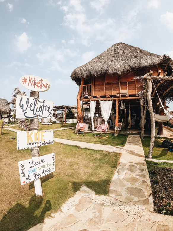A wooden house with a thatched roof and a sign that says welcome.