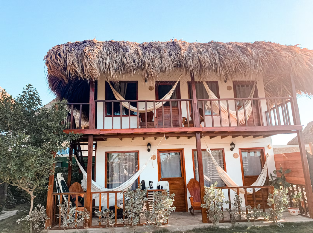 A house with a thatched roof and hammocks on the porch.