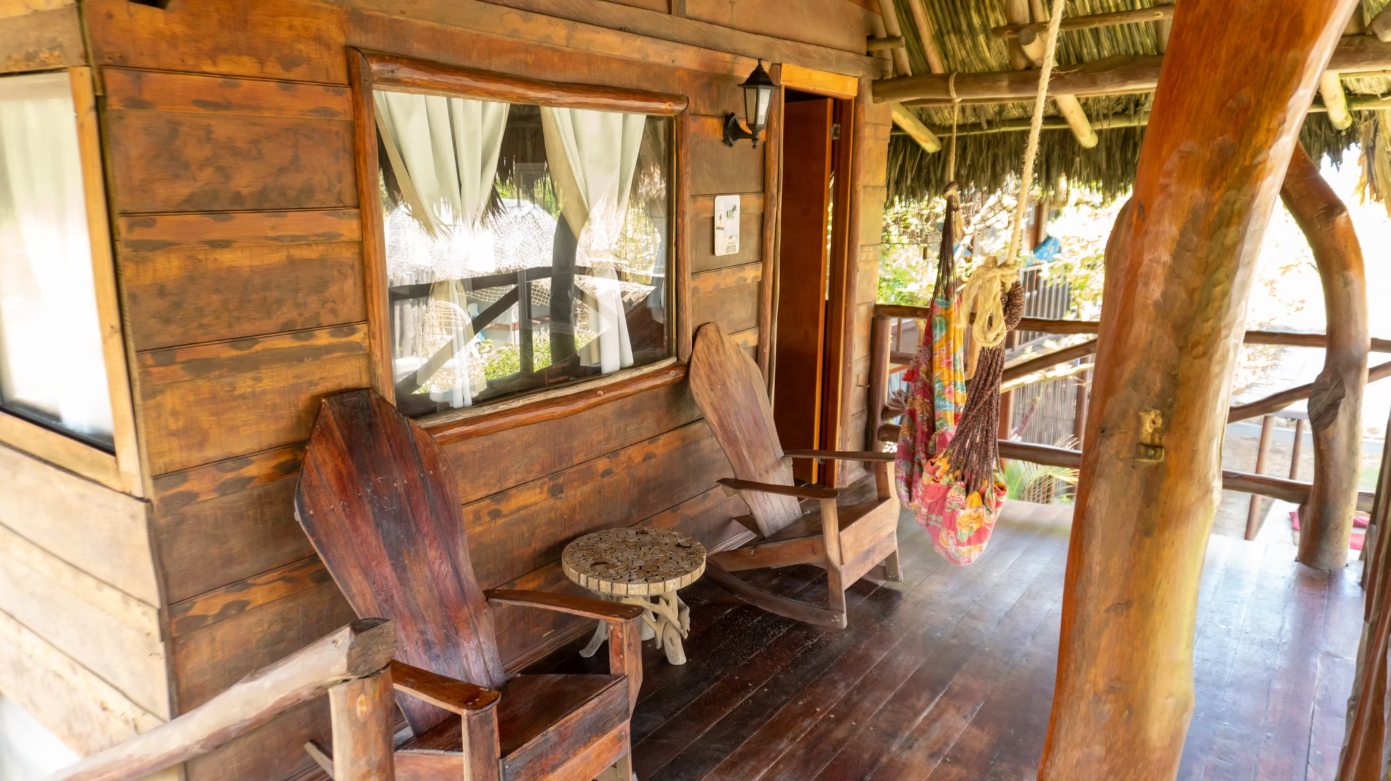 A wooden porch with chairs , a table and a hammock.