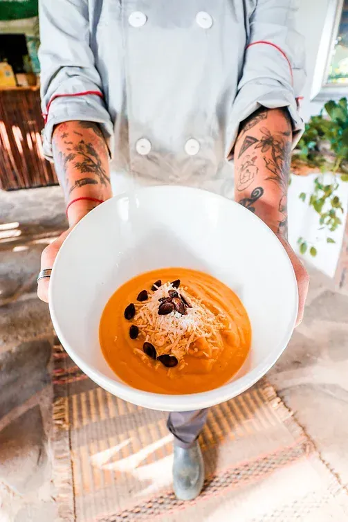 A chef is holding a bowl of soup in his hands.