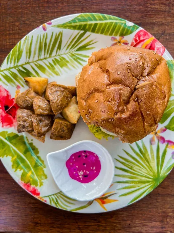 A plate of food with a hamburger and potatoes on a wooden table.