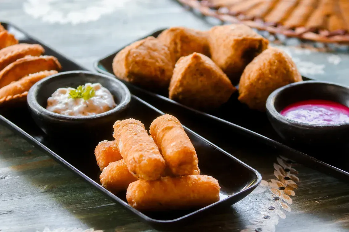 Two plates of food with dipping sauces on a table.