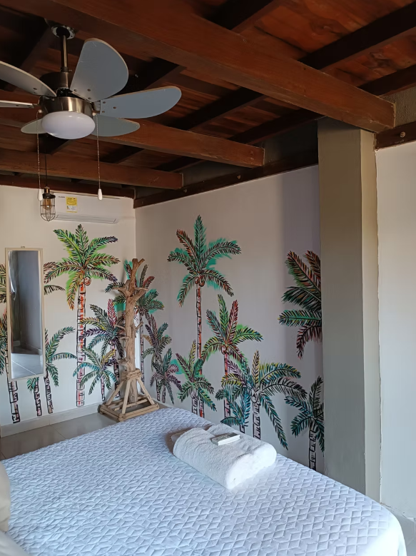 A bedroom with a ceiling fan and palm trees on the wall