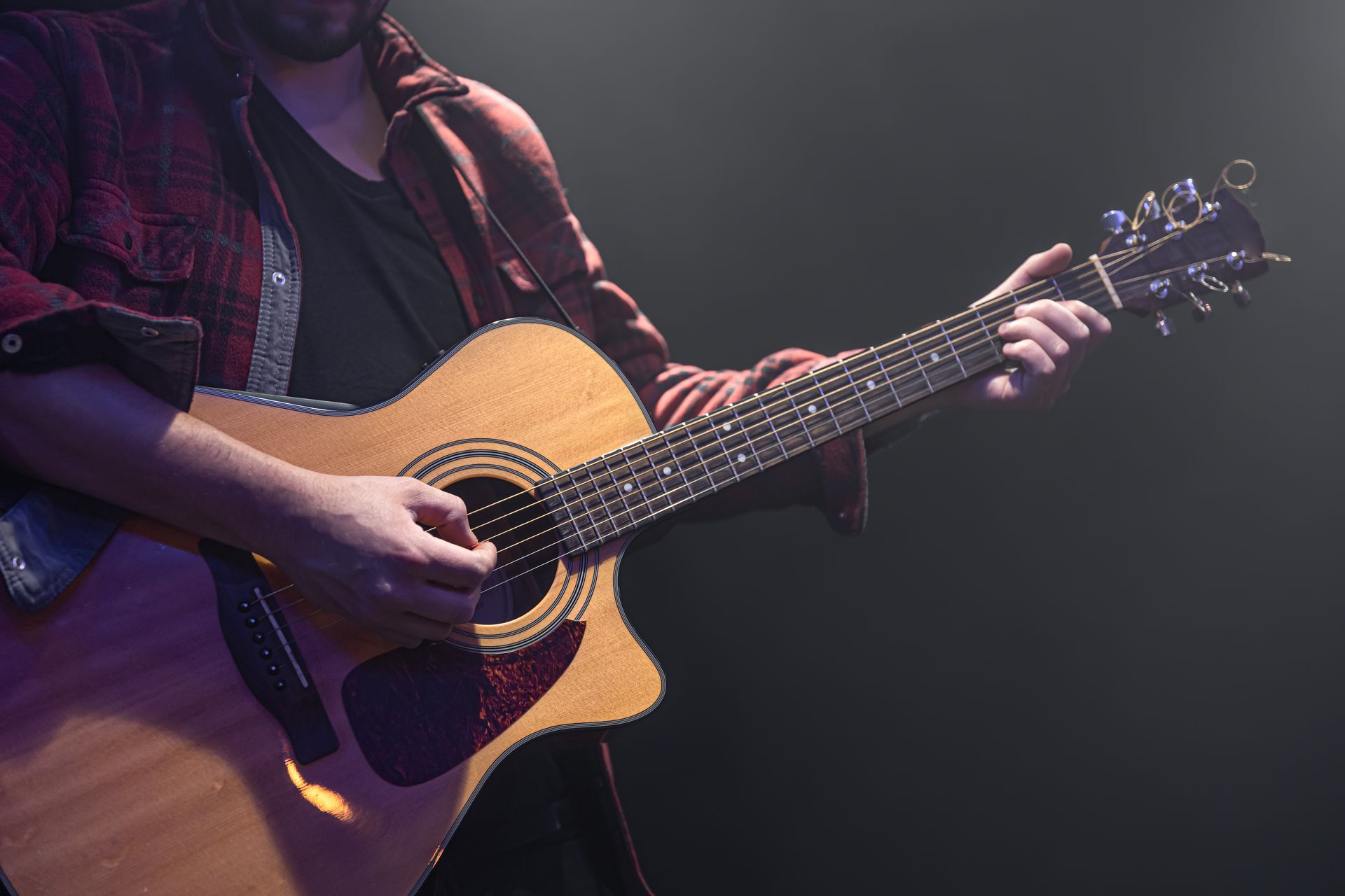 A man is playing an acoustic guitar on a stage.