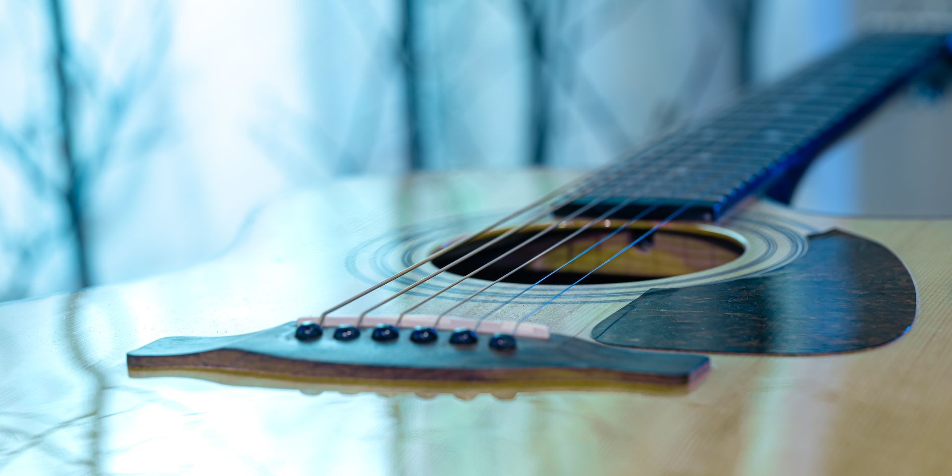 A close up of an acoustic guitar on a table.