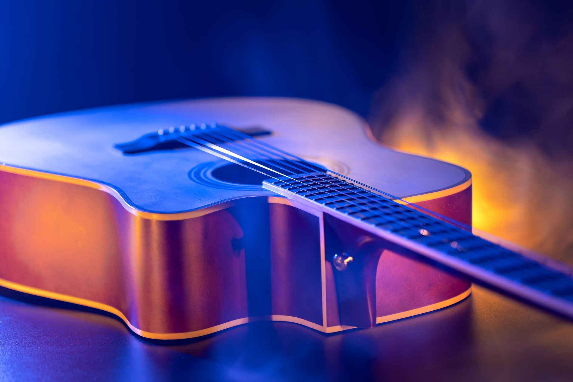 A close up of an acoustic guitar sitting on a table.