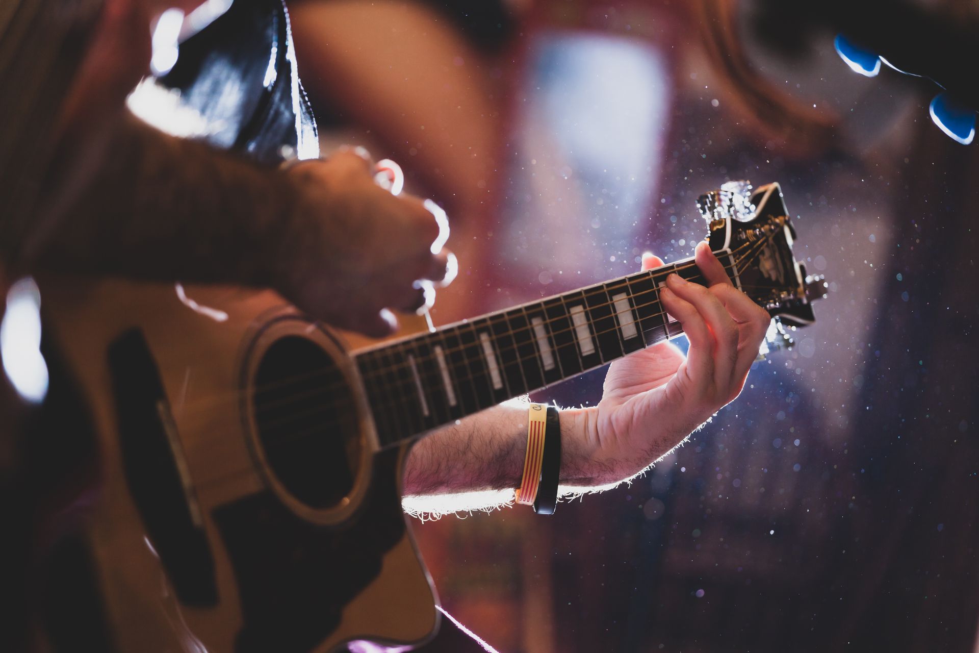 A person is playing an acoustic guitar in a dark room.