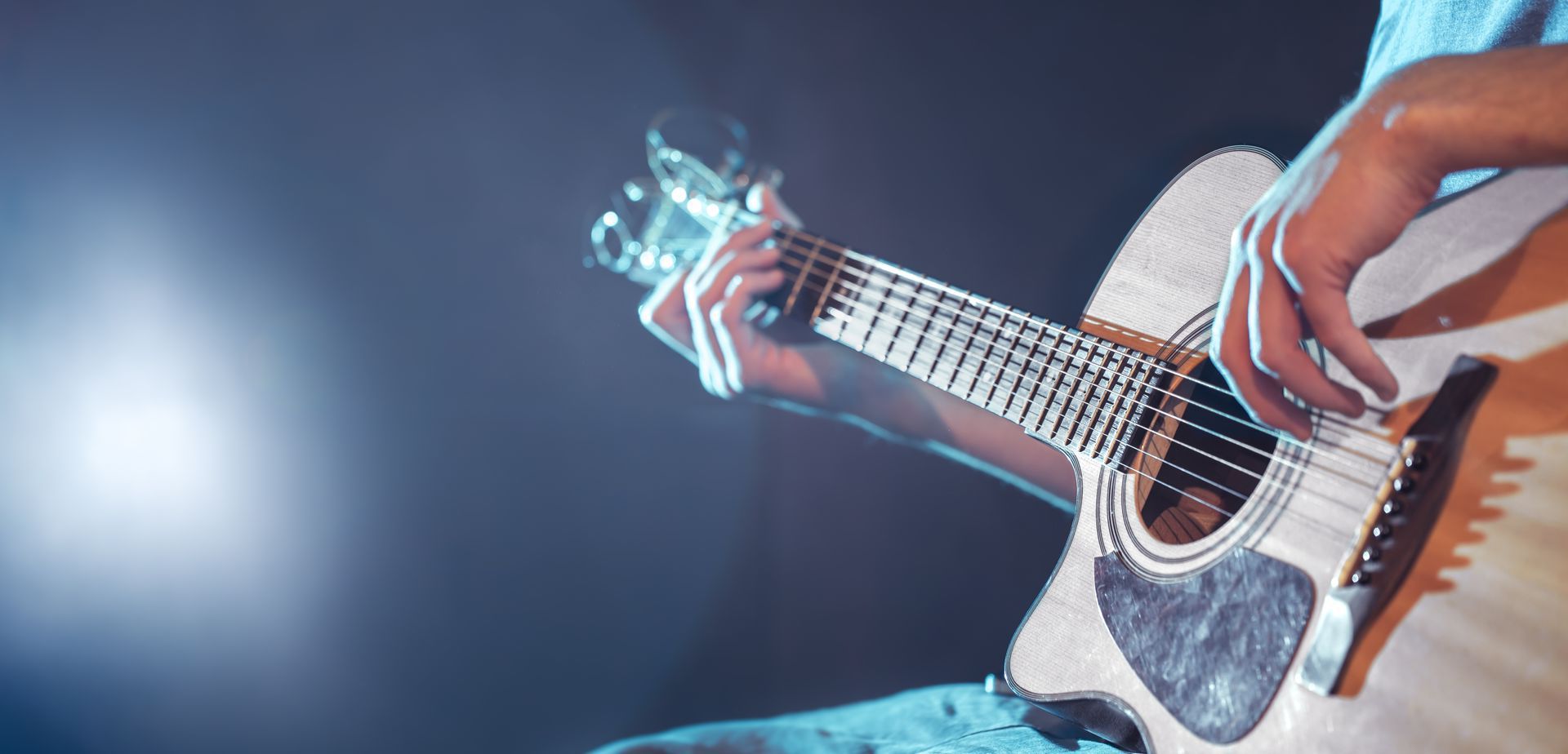 A person is playing an acoustic guitar on a stage.