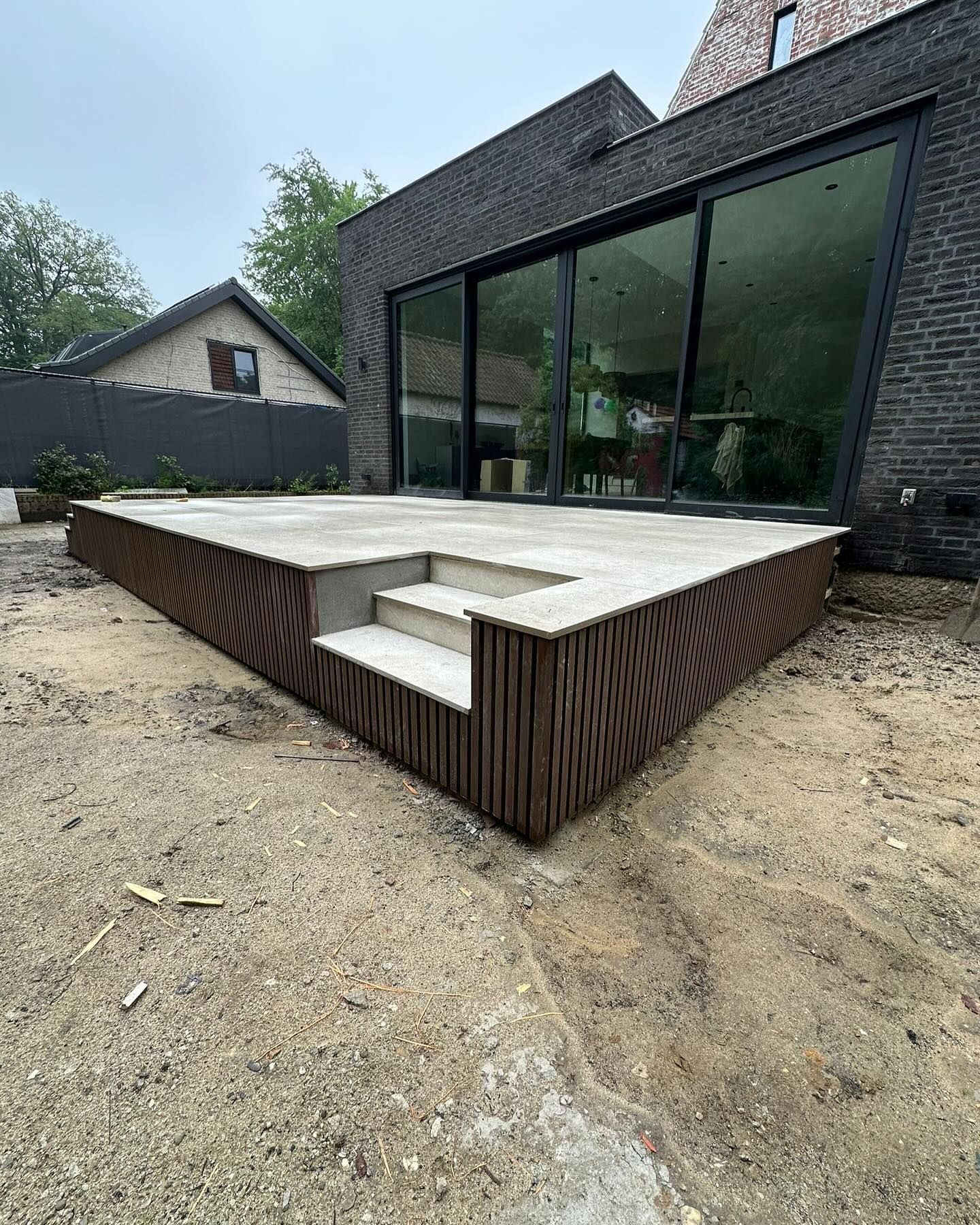 Een groot bakstenen huis met een terras en een trap ervoor.